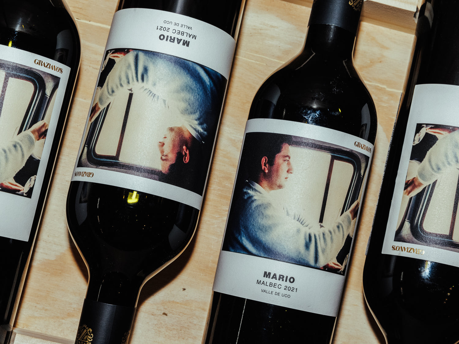 Wine bottles with unique labels featuring artistic depictions on a wooden surface.