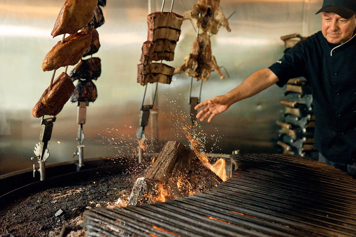 Asador cook with skewers over the fire at Graziano's
