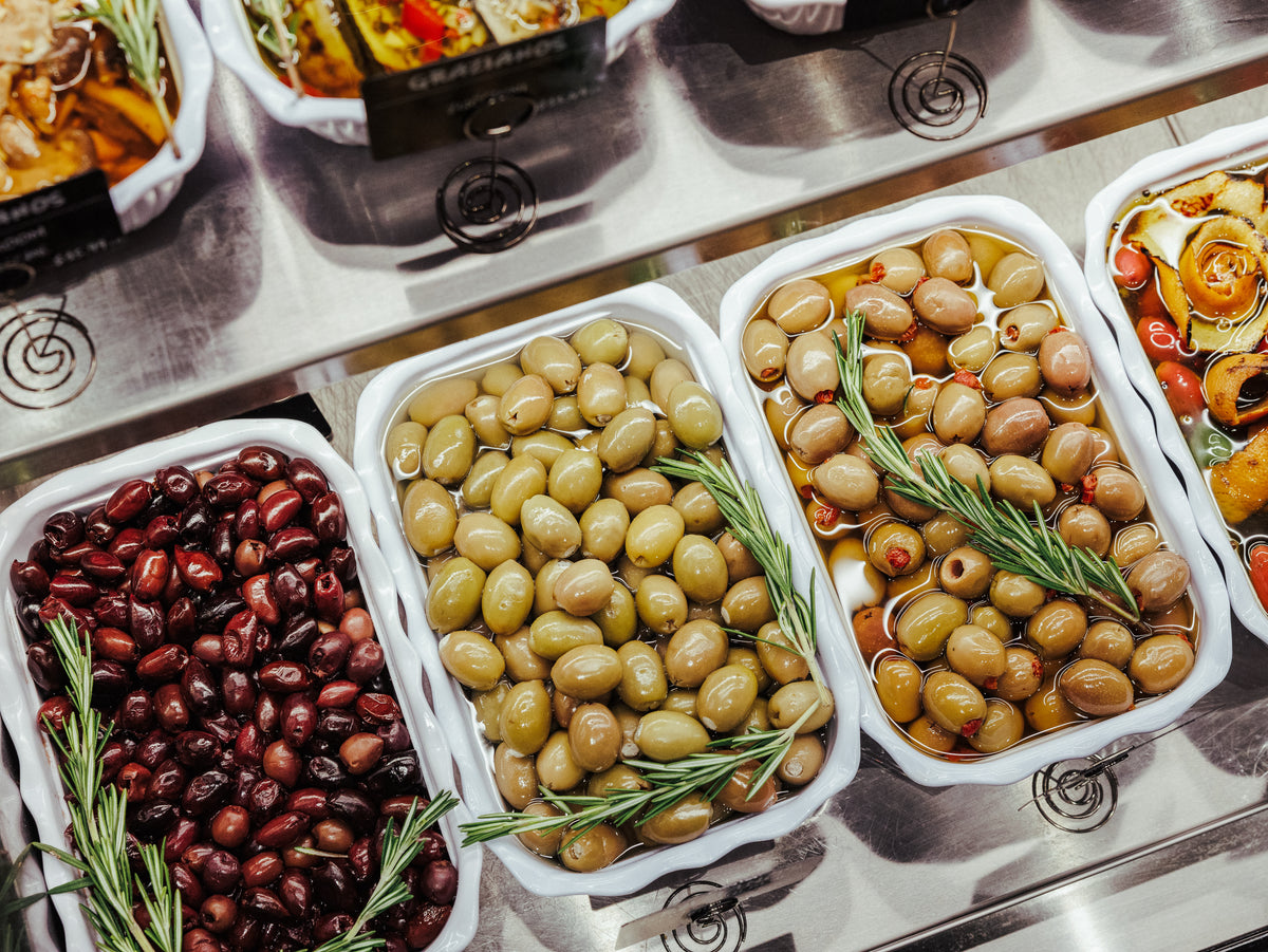 Assorted olives in white containers on a metal surface