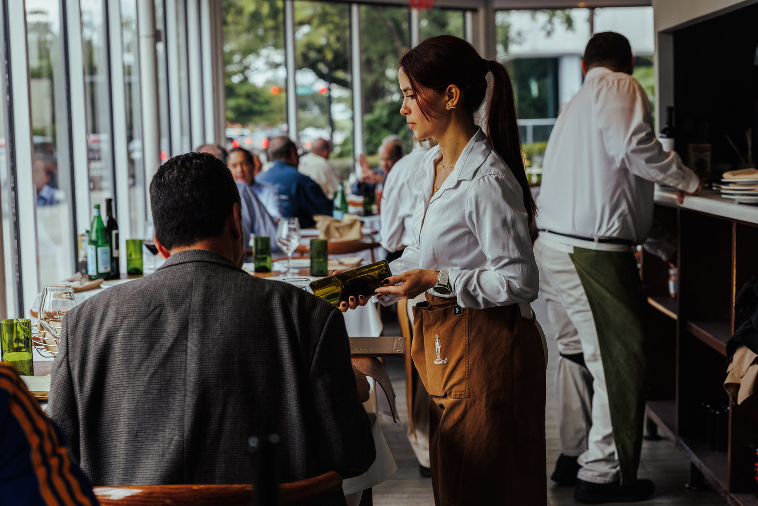 Waitress holding a bottle of wine in a restaurant setting