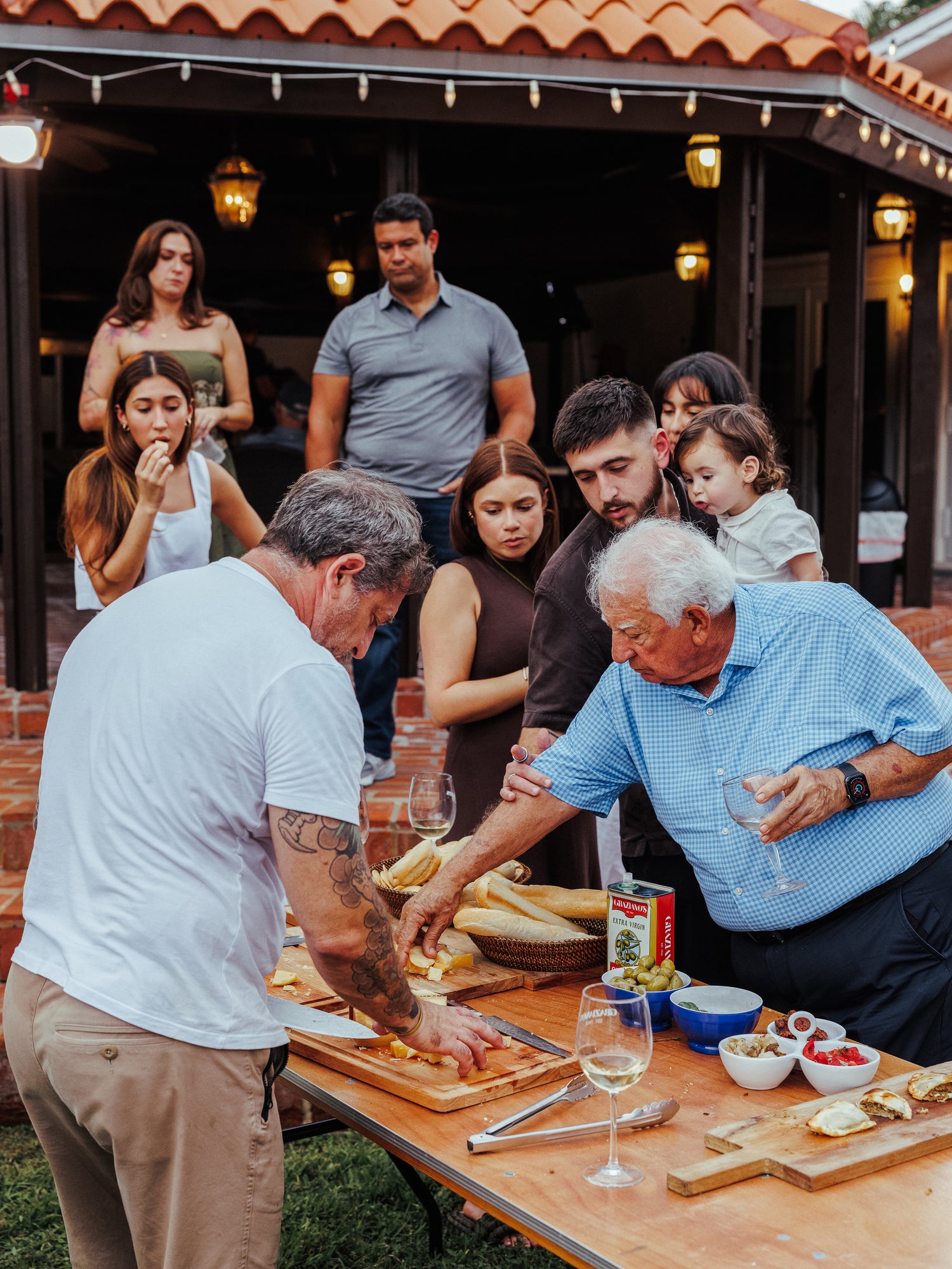 Family gathering around a table outdoors, preparing food together.